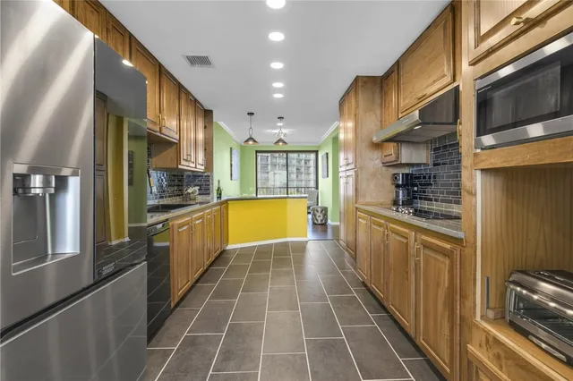 a kitchen with a sink stainless steel appliances wooden floor and cabinets