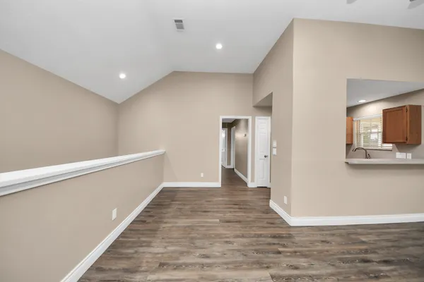 an empty room with wooden floor chandelier fan and windows