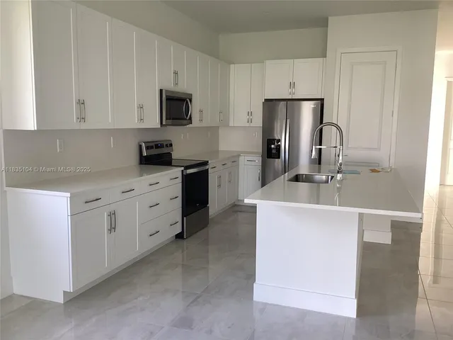 a kitchen with cabinets stainless steel appliances and sink
