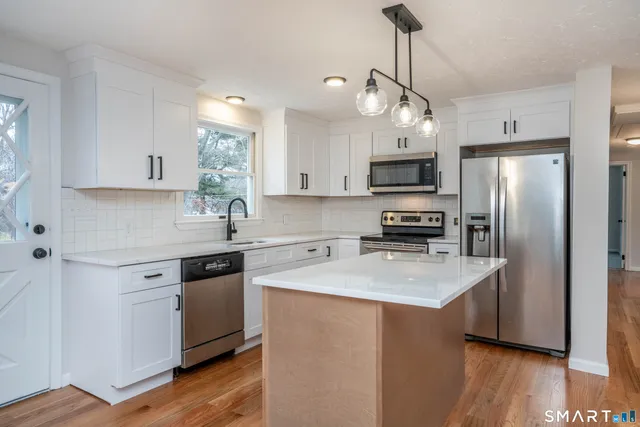 a kitchen with stainless steel appliances granite countertop a stove refrigerator sink and microwave