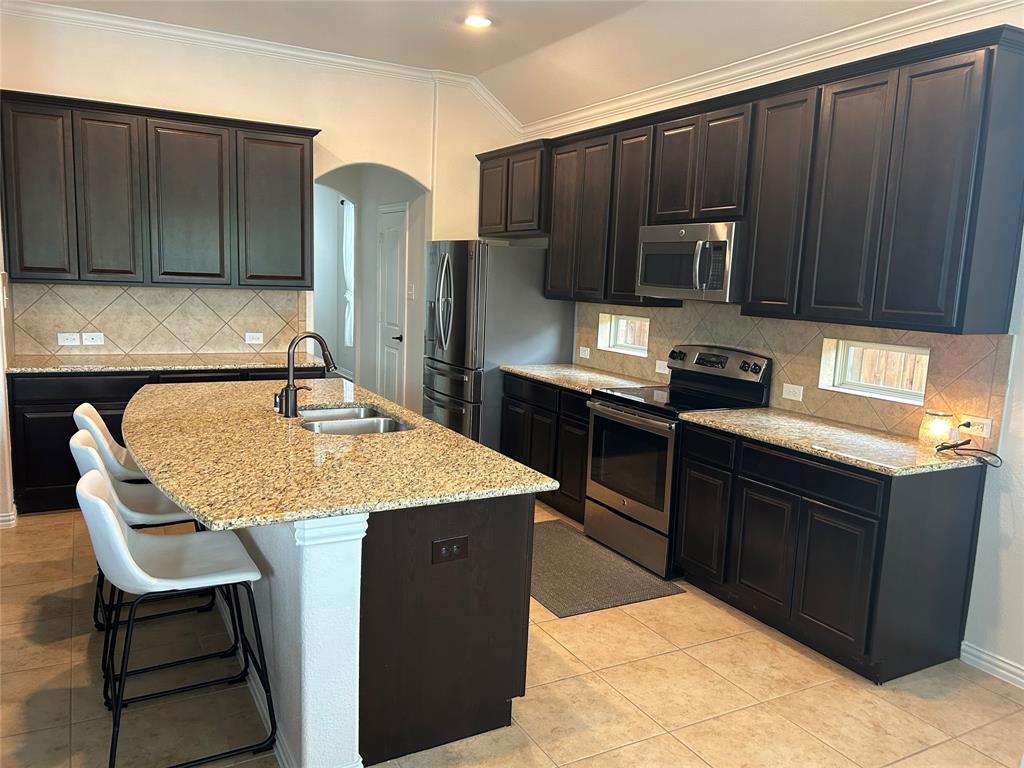 16117 Harper Road Prosper, TX 75078 - Photo 3 of 8 a kitchen with stainless steel appliances granite countertop a sink counter space and cabinets
