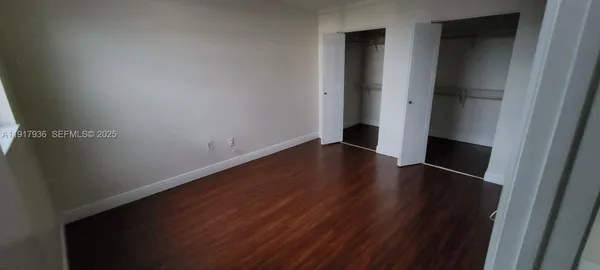 an empty room with wooden floor and closet
