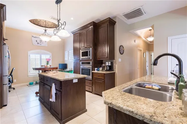 a kitchen with granite countertop a sink a counter top space appliances and cabinets