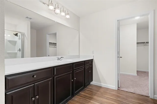 a spacious bathroom with a granite countertop sink a mirror and a shower