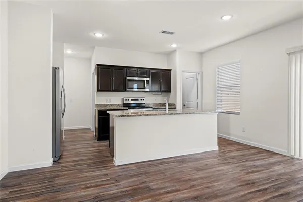 a view of kitchen with microwave stove refrigerator and cabinets