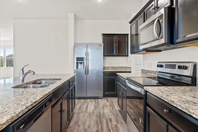 a kitchen with stainless steel appliances granite countertop a sink stove and refrigerator