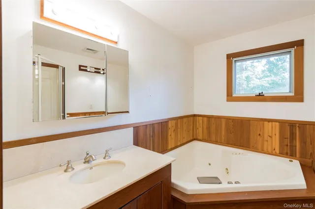 a bathroom with a tub sink and mirror
