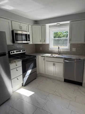 a kitchen with stainless steel appliances granite countertop a stove a sink and a microwave