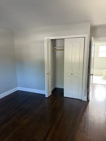a view of empty room with wooden floor and closet