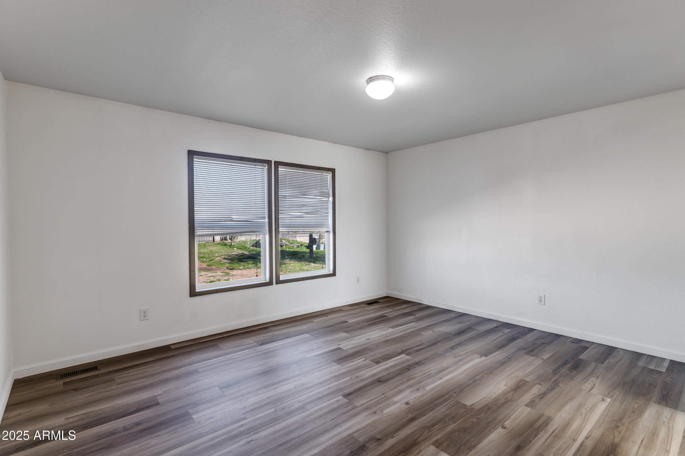 11341 East 6th Avenue Apache Junction, AZ 85120 - Photo 24 of 37 an empty room with wooden floor and windows