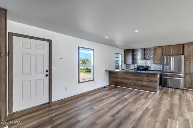 a kitchen with stainless steel appliances a refrigerator and a wooden floor