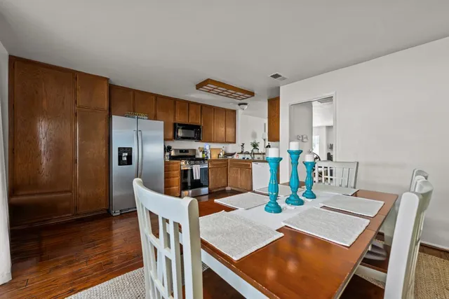 a kitchen with stainless steel appliances granite countertop a refrigerator a stove top oven a dining table and chairs