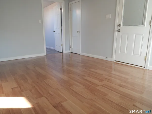 a view of an empty room with wooden floor and a window