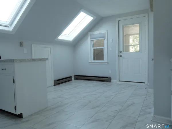 a view of an empty room with closet and a window
