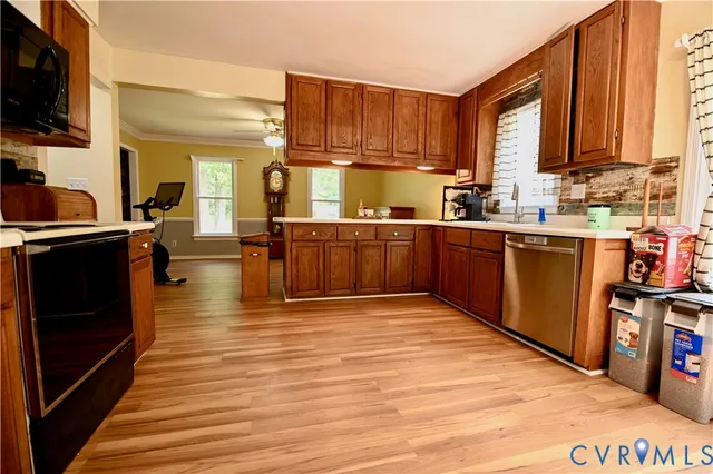 a kitchen with stainless steel appliances granite countertop a stove top oven a sink dishwasher and wooden cabinets with wooden floor