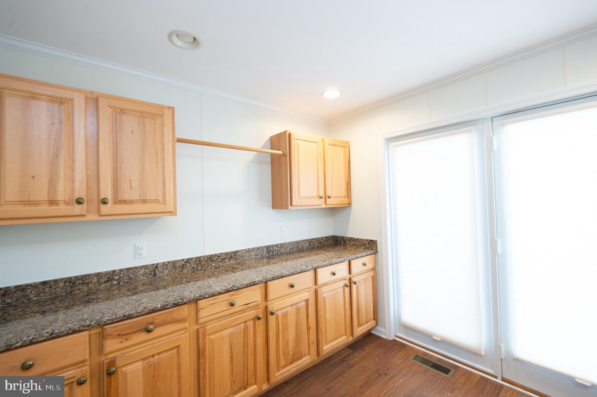 409 Bayly Avenue Cambridge, MD 21613 - Photo 28 of 54 a kitchen with granite countertop white cabinets and a wooden floor