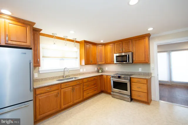a kitchen with stainless steel appliances granite countertop a stove a sink a refrigerator and cabinets