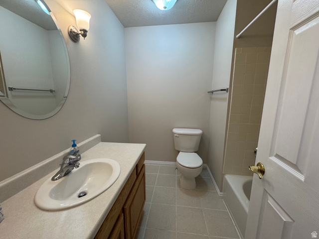 88 Canterbury Lane Logan, UT 84321 - Photo 17 of 37 Bathroom featuring a vanity with an integrated sink, wood-finish cabinetry, a wall-mounted mirror, a toilet, and a combination tub/shower with tiled surround