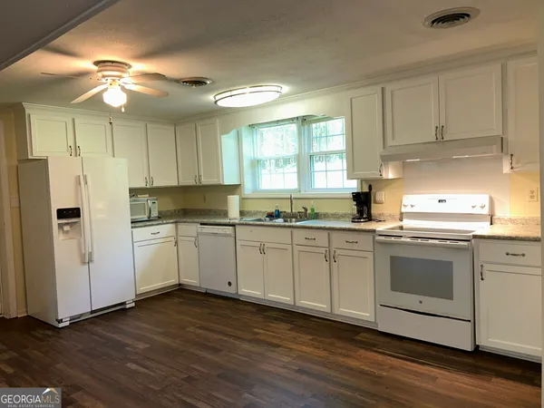 a kitchen with granite countertop white cabinets and white appliances