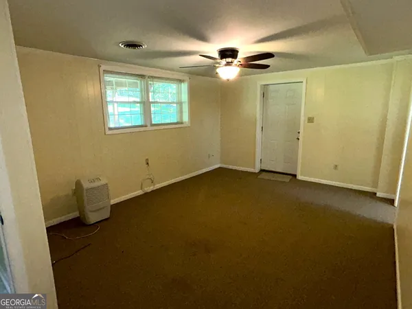 an empty room with windows and fan