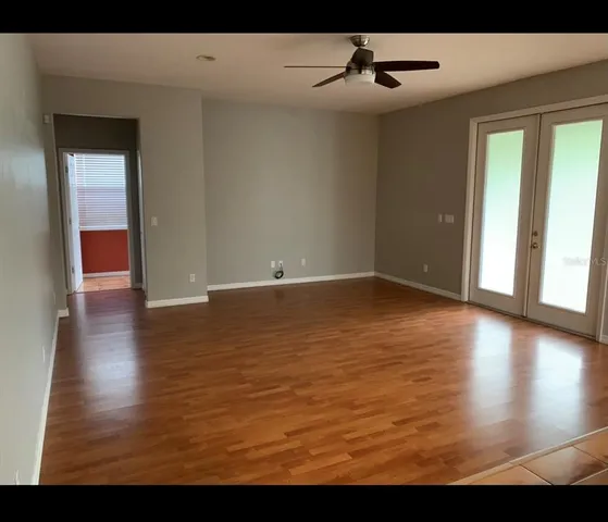 a view of an empty room with window and wooden floor
