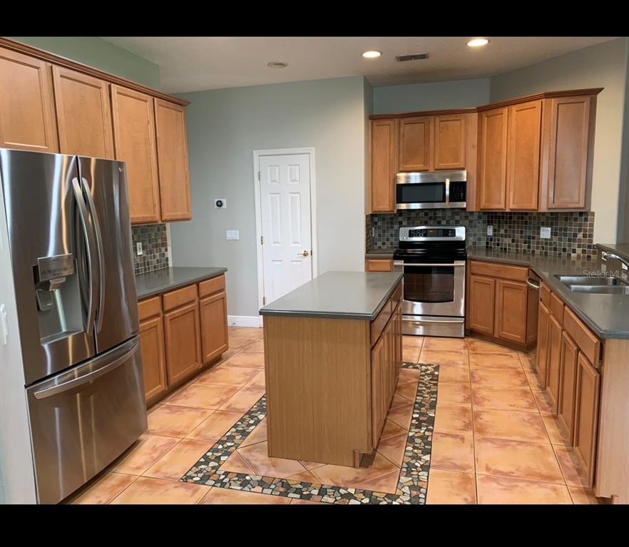 761 Broadoak Loop Sanford, FL 32771 - Photo 19 of 22 a kitchen with stainless steel appliances granite countertop a refrigerator sink and stove