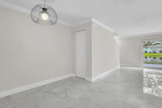 an empty room with kitchen view and wooden floor