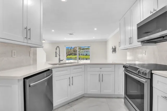 a kitchen with white cabinets appliances and a sink