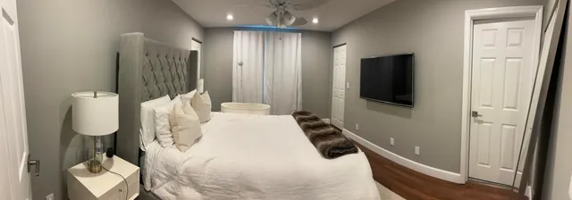 a bedroom with a bed and a flat tv screen on wall