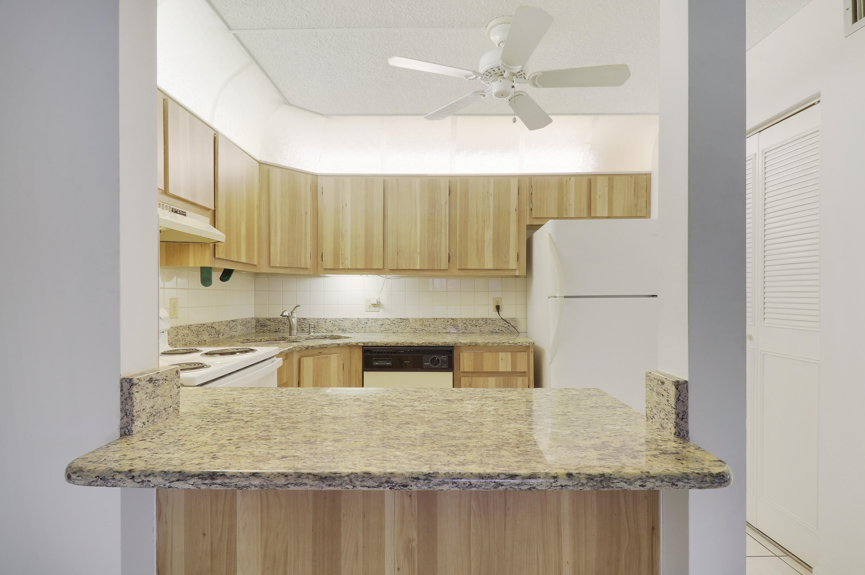 335 Knotty Pine Circle, Unit D1 Greenacres, FL 33463 - Photo 6 of 18 a kitchen with kitchen island granite countertop a sink a counter top space and cabinets