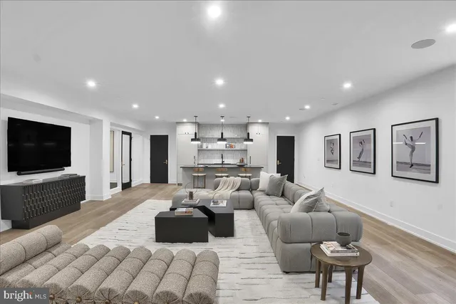 a living room with furniture kitchen view and a wooden floor