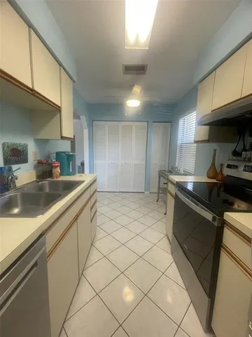 a kitchen with stainless steel appliances a sink dishwasher stove refrigerator and cabinets