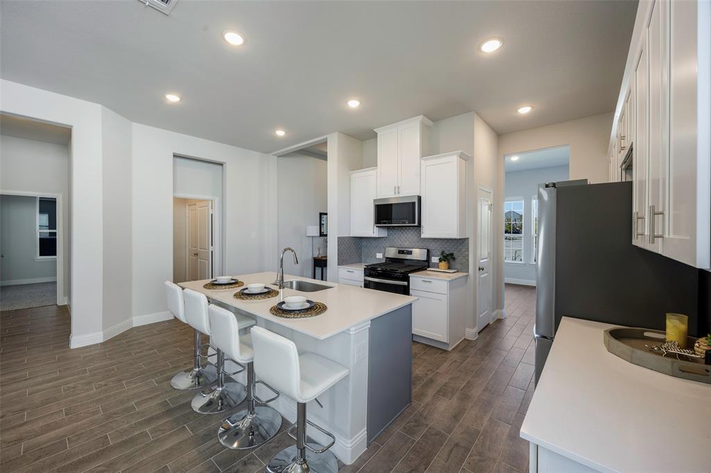 1617 Hitching Post Road Weston, TX 75009 - Photo 6 of 30 a kitchen with stainless steel appliances kitchen island granite countertop a refrigerator a stove top oven a sink a dining table and chairs with wooden floor