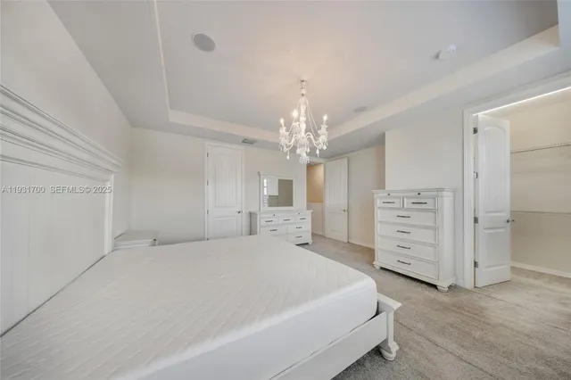 a spacious bedroom with a bed and a chandelier
