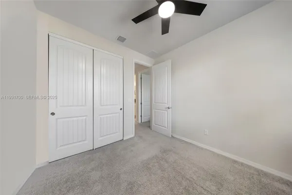 an empty room with a ceiling fan and carpet