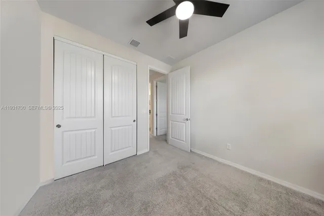 an empty room with a ceiling fan and carpet