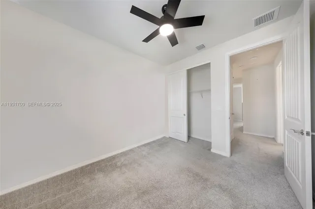 an empty room with ceiling fan and windows