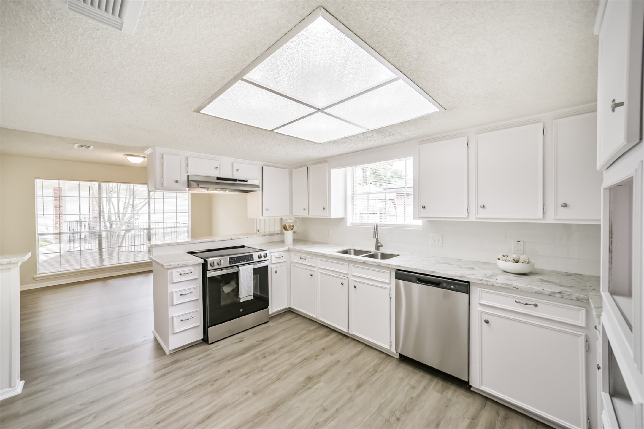 1011 Baltic Lane Houston, TX 77090 - Photo 11 of 43 a kitchen with a stove a sink and white cabinets with wooden floor