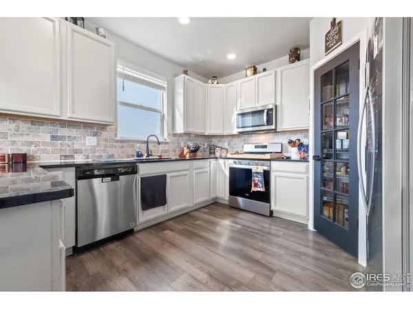 a kitchen with stainless steel appliances granite countertop a refrigerator a stove and a sink with wooden cabinets