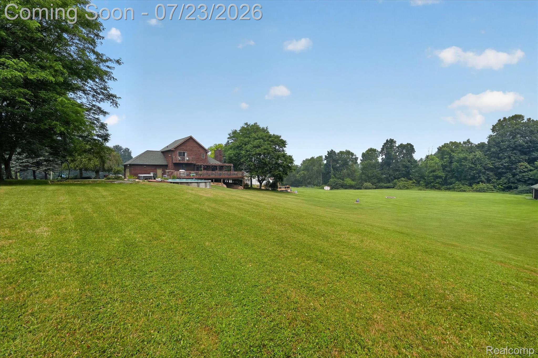 2795 Bird Road Ortonville, MI 48462 - Photo 51 of 62 Expansive green lawn surrounds a multi-story residence featuring a wood-sided exterior, a multi-level deck, and an outdoor pool
