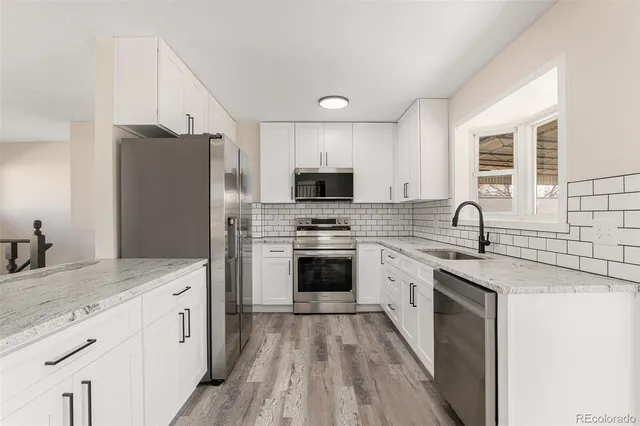 a kitchen with granite countertop white cabinets and stainless steel appliances