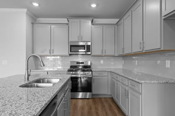 a kitchen with stainless steel appliances granite countertop a sink stove refrigerator and cabinets