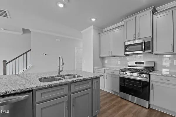 a kitchen with granite countertop a sink cabinets and stainless steel appliances