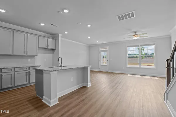 a kitchen with stainless steel appliances granite countertop a stove a sink and white cabinets with wooden floor next to windows