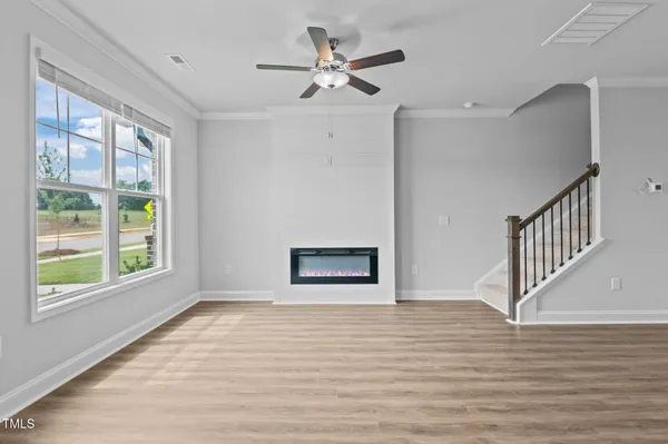 a view of an empty room with a window and wooden floor