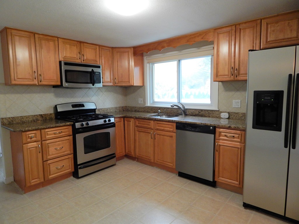 115 Desoto Road Boston, MA 02132 - Photo 4 of 21 a kitchen with stainless steel appliances granite countertop a stove top oven a sink dishwasher and a refrigerator with wooden cabinets