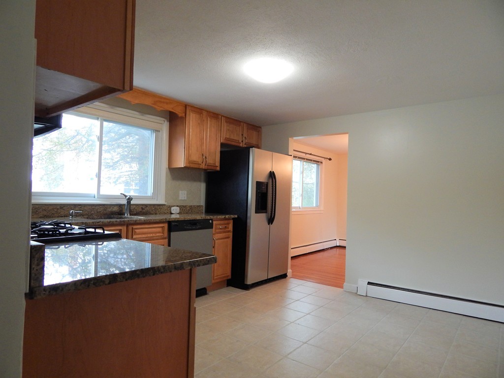 115 Desoto Road Boston, MA 02132 - Photo 5 of 21 a kitchen with stainless steel appliances granite countertop a refrigerator a sink dishwasher a stove and white countertops with wooden floor