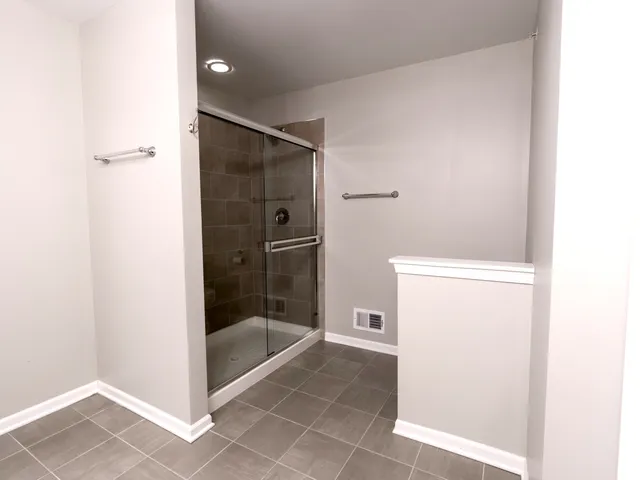 an empty room with a chandelier fan and windows