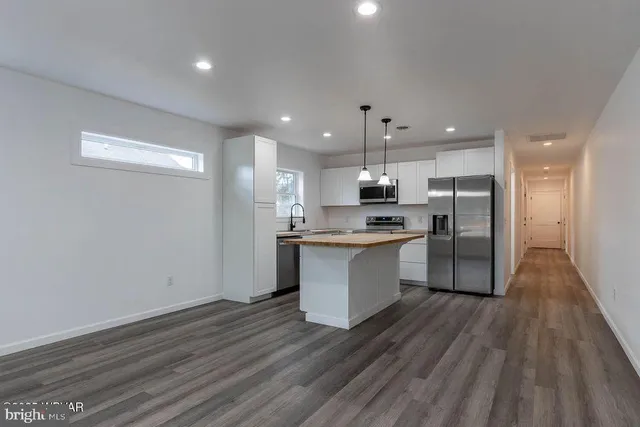 a large kitchen with a center island wooden floor stainless steel appliances and a window