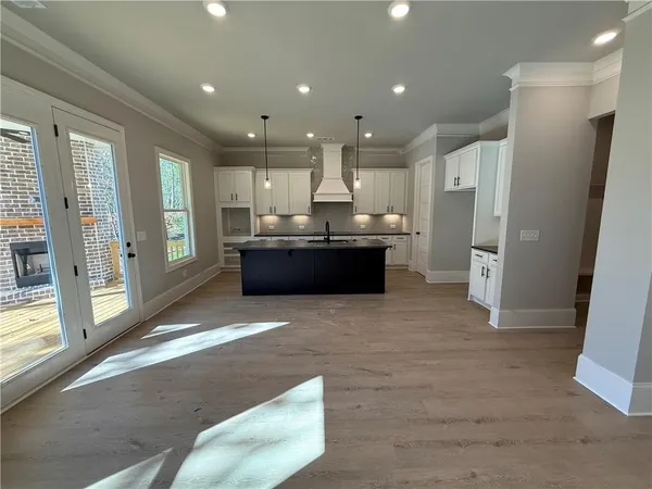 a large kitchen with stainless steel appliances kitchen island granite countertop a stove a sink dishwasher a refrigerator and white cabinets with wooden floor